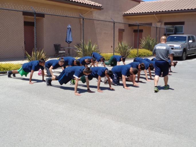 Young men and women doing push ups outside.